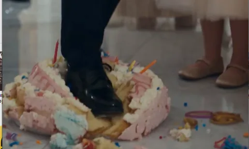 Travis climbs onto Penny’s birthday table and deliberately crushes her decorated cake beneath both shoes. Frosting and candles scatter across the marble while Penny recoils in shock.