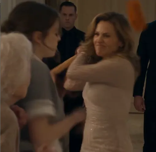 Veronica swings the wooden-handled mop hard toward Eleanor.